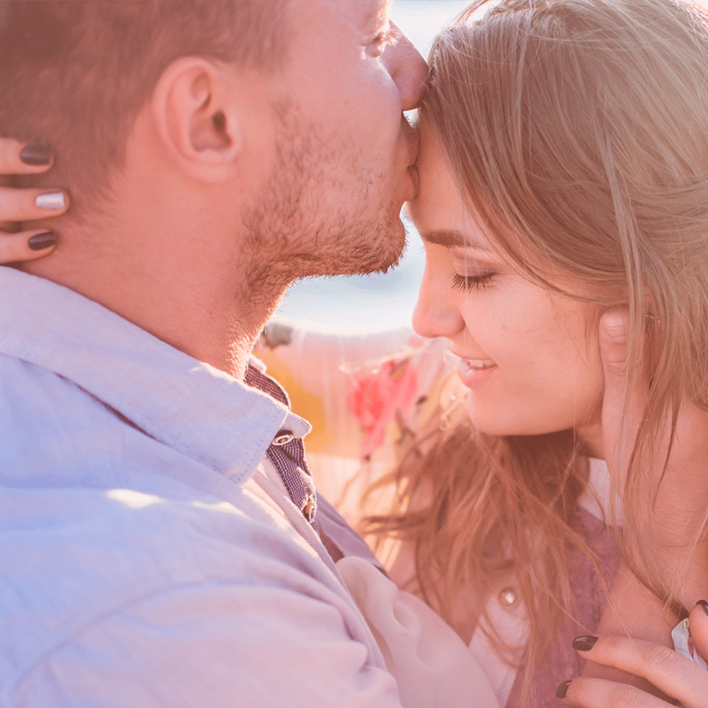 Fertilização in vitro e psicologia:  Casal abraçado e homem beijando testa da mulher.