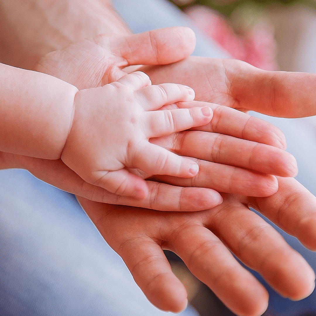 Três mãos juntas: do pai, da mãe e do bebê